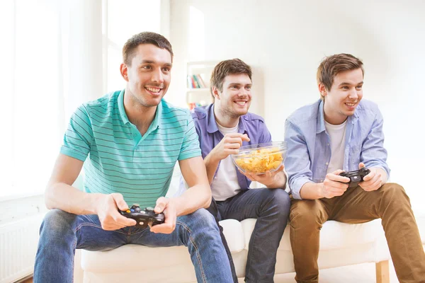 Amigos sonrientes jugando videojuegos en casa — Foto de Stock