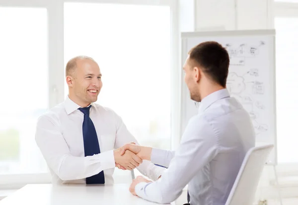 Twee Glimlachende zakenmensen schudden handen in office — Stockfoto