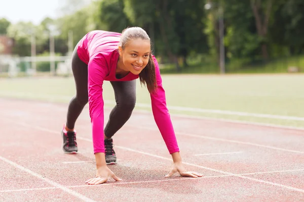 Sonriente joven corriendo en pista al aire libre — Foto de Stock