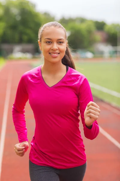 Femme souriante courir sur la piste à l'extérieur — Photo