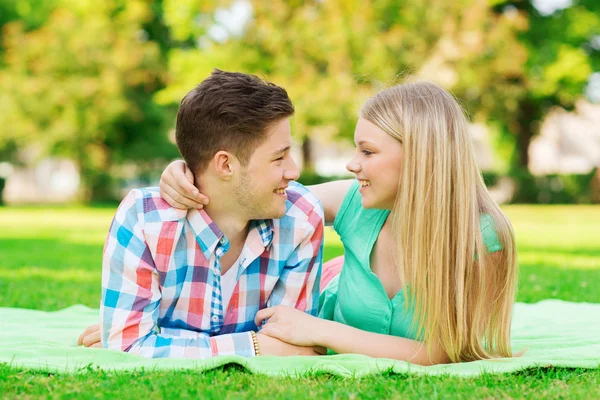 Sorrindo casal deitado em cobertor no parque — Fotografia de Stock