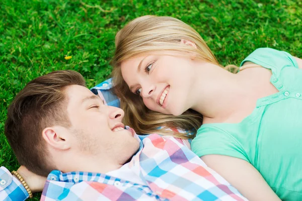 Smiling couple lying on grass in park — Stock Photo, Image