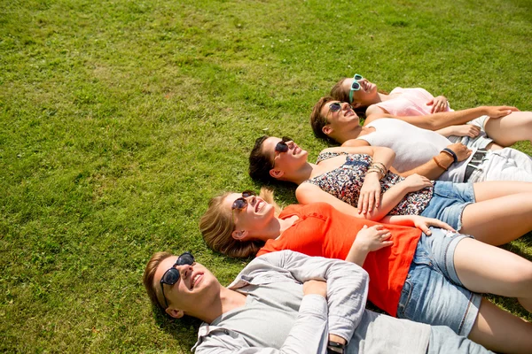 Grup de prieteni zâmbitori întinși pe iarbă în aer liber — Fotografie, imagine de stoc