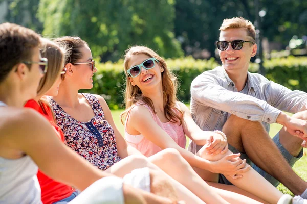 Группа улыбающихся друзей на открытом воздухе, сидящих в парке — стоковое фото