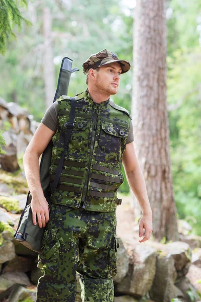 Young soldier or hunter with gun in forest — Stock Photo, Image