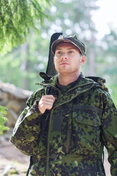 Young soldier or hunter with gun in forest — Stock Photo, Image