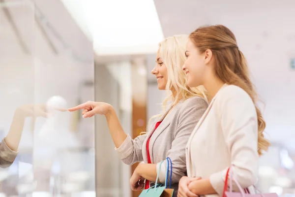 Gelukkig jonge vrouwen met boodschappentassen in winkelcentrum — Stockfoto