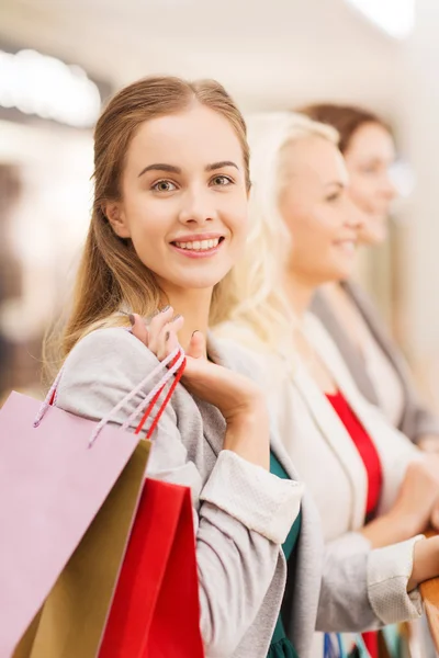 Happy young women with shopping bags in mall — Stock Photo, Image