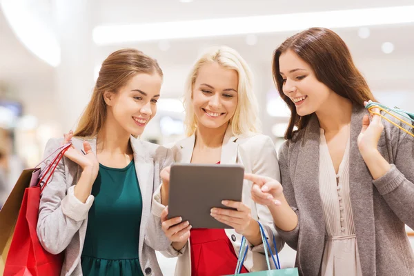 Gelukkig jonge vrouwen met tablet pc en shopping tassen — Stockfoto