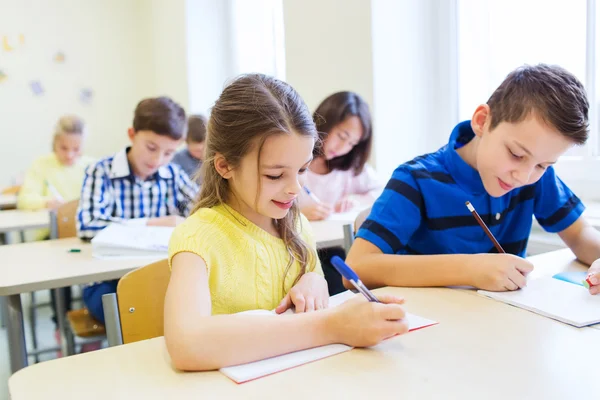 Grupp av skolbarnen skriva prov i klassrummet — Stockfoto