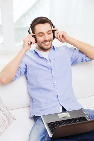 Sorrindo homem com laptop e fones de ouvido em casa Imagens Royalty-Free