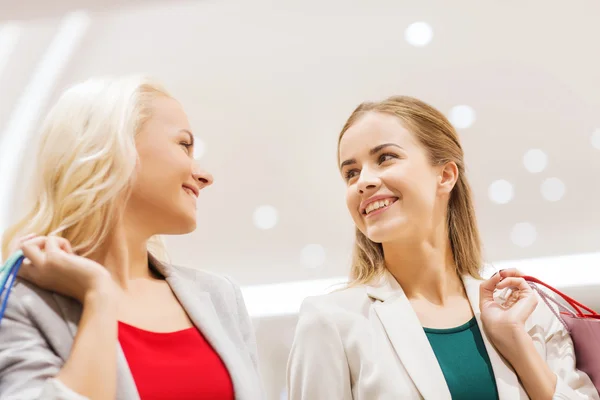 Mulheres jovens felizes com sacos de compras no shopping — Fotografia de Stock