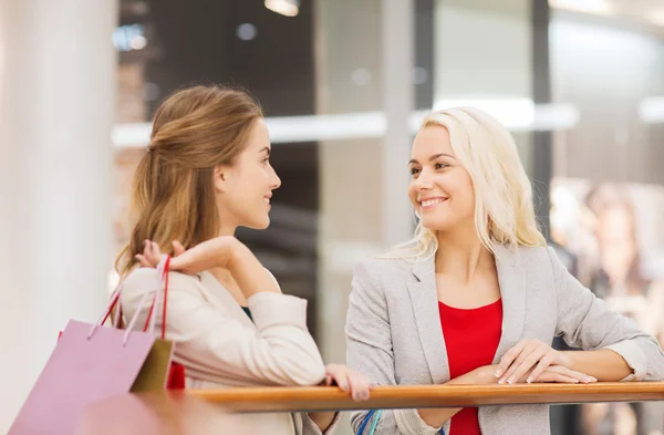 Mulheres jovens felizes com sacos de compras no shopping — Fotografia de Stock