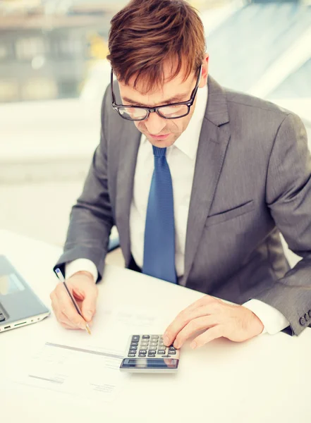 Zakenman met computer, papers en rekenmachine — Stockfoto