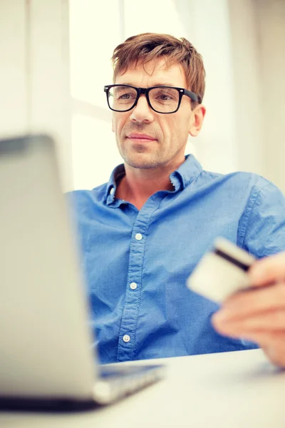 Homem com laptop e cartão de crédito em casa — Fotografia de Stock
