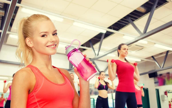 Femme sportive souriante avec bouteille d'eau — Photo