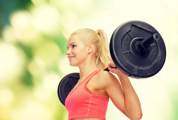 Smiling sporty woman exercising with barbell — Stock Photo, Image