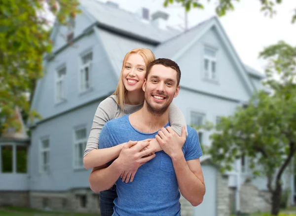 Lächelndes Paar umarmt sich vor Haus-Hintergrund — Stockfoto