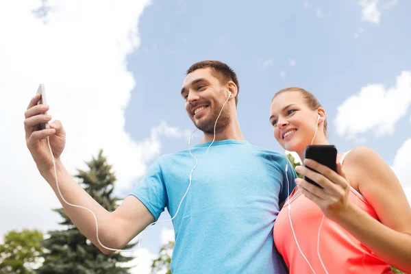 Twee lachende mensen met smartphones outdoors — Stockfoto