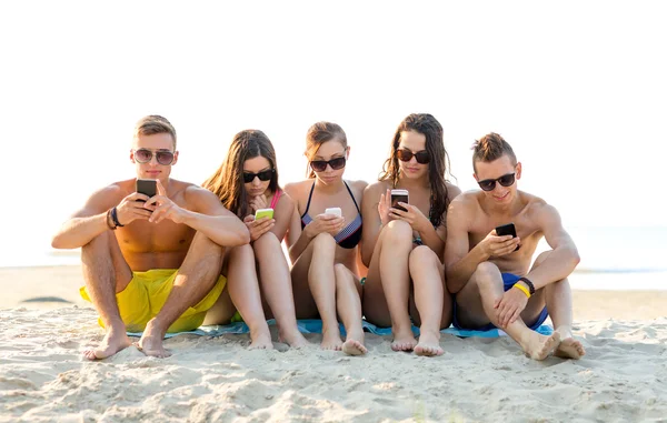 Vänner med smartphones på stranden — Stockfoto