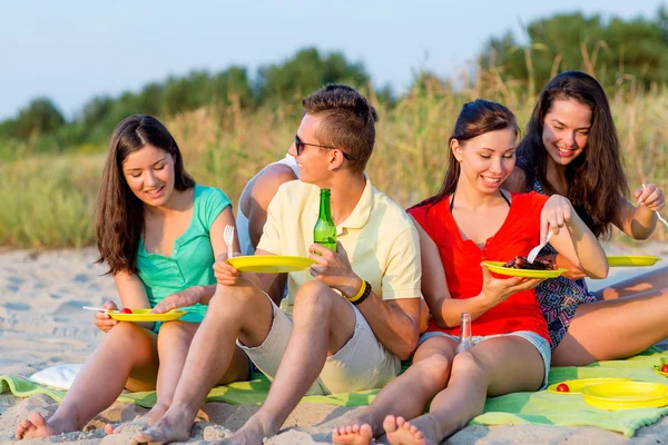 Lachende vrienden zittend op zomer strand — Stockfoto