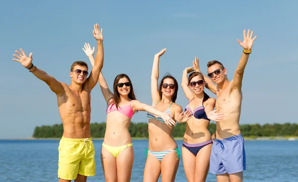 Amigos sonrientes en gafas de sol en la playa de verano —  Fotos de Stock