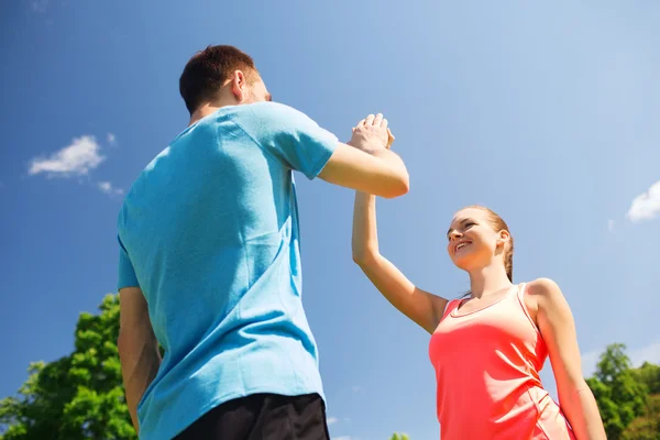 Zwei lächelnde Menschen, die draußen hoch fünf machen — Stockfoto