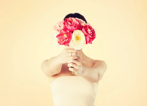 Mujer sosteniendo ramo de flores sobre su cara — Foto de Stock