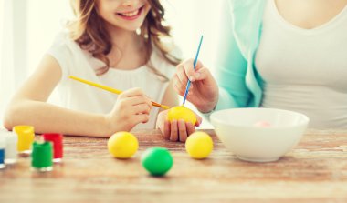 close up of little girl and mother coloring eggs clipart