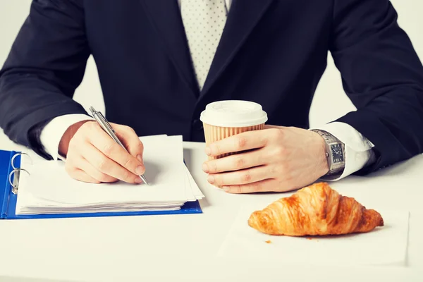 Businessman with coffee writing something — Stock Photo, Image