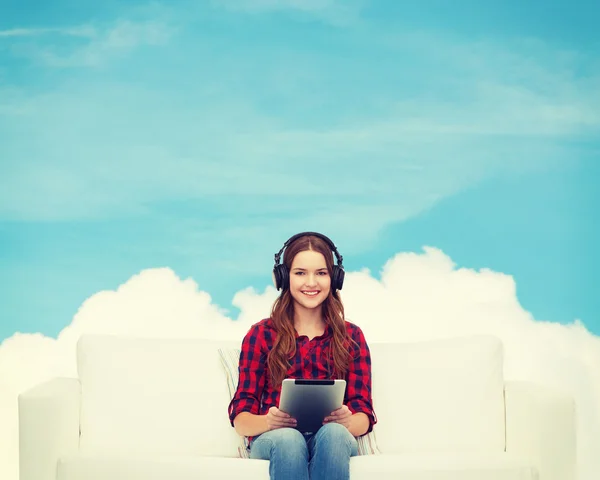 Girl sitting on sofa with headphones and tablet pc — Stock Photo, Image