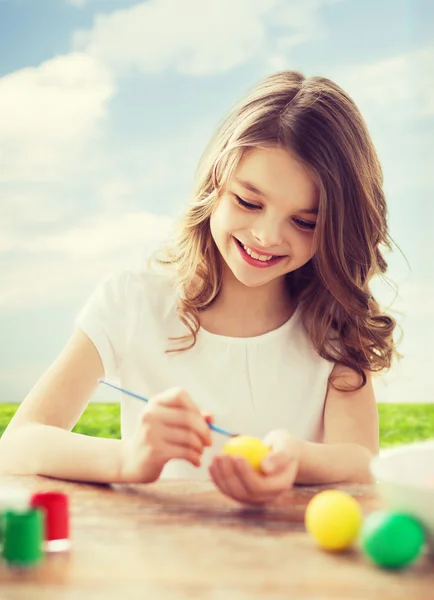 Lächelndes kleines Mädchen, das Eier für Ostern färbt — Stockfoto