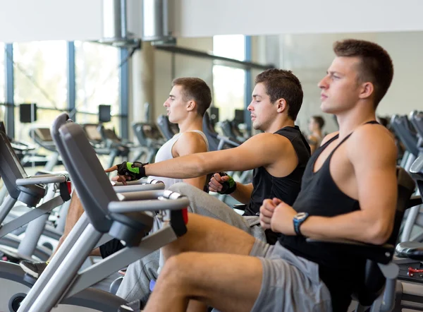 Hombres haciendo ejercicio en bicicleta estática en el gimnasio —  Fotos de Stock