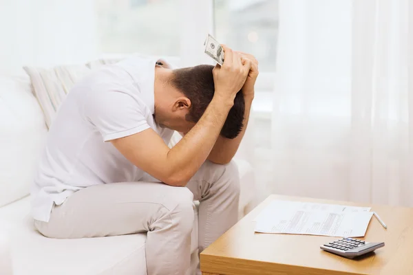 Hombre con dinero y calculadora en casa — Foto de Stock