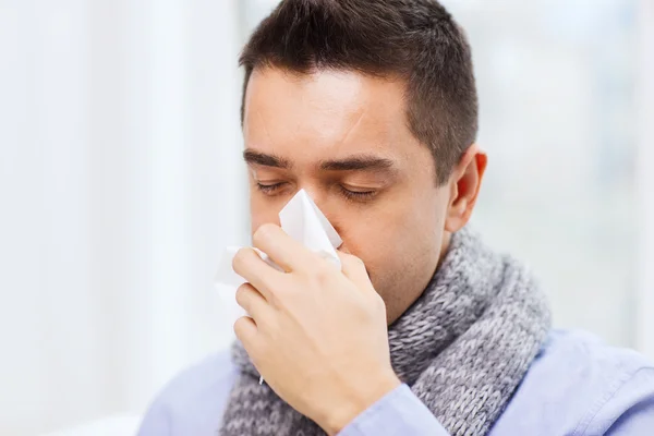 Close up of ill man with flu blowing nose at home — Stock Photo, Image