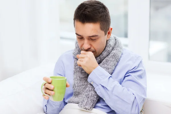 Homem doente com gripe bebendo chá e tosse em casa Imagens Royalty-Free