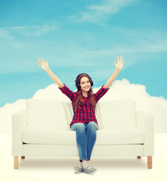 Tonårig flicka sitter på soffan med hörlurar — Stockfoto