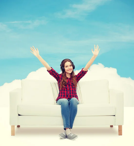 Teenage girl sitting on sofa with headphones — Stock Photo, Image