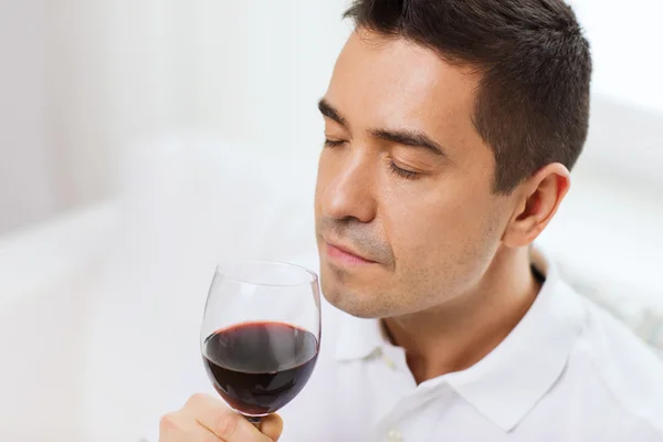 Glücklicher Mann, der zu Hause Rotwein aus Glas trinkt — Stockfoto