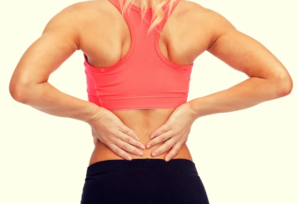 Крупным планом спортивная женщина, касающаяся своей спины — стоковое фото