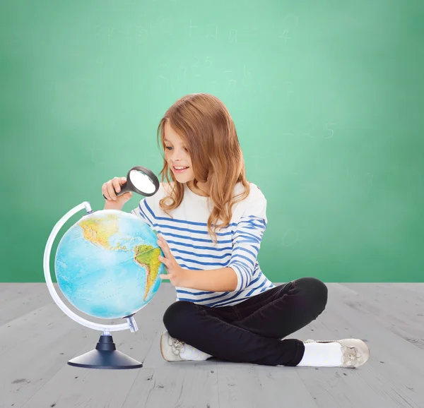 Menina feliz olhando globo com lupa — Fotografia de Stock