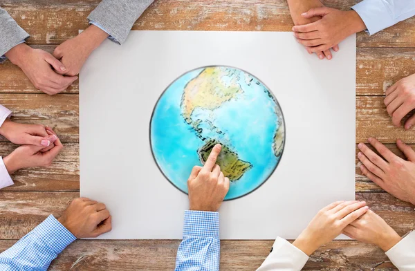 Close up of hands with globe picture at table — Stock Photo, Image