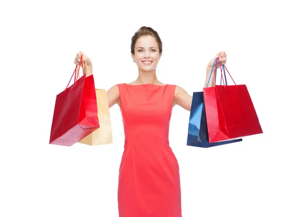Lachende elegante vrouw in jurk met shopping tassen — Stockfoto
