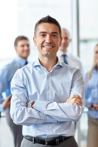 Usměvavý obchodník s kolegy v kanceláři — Stock fotografie