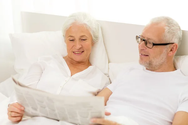 Glückliches Seniorenpaar mit Zeitung im Bett — Stockfoto