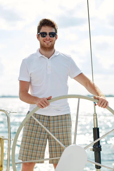 Young man in sunglasses steering wheel on yacht — Stock Photo, Image