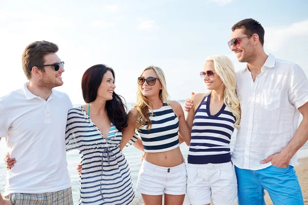 Улыбающиеся друзья в солнечных очках разговаривают на пляже — стоковое фото