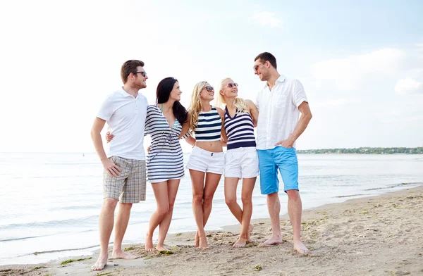 Lächelnde Freunde mit Sonnenbrille unterhalten sich am Strand — Stockfoto