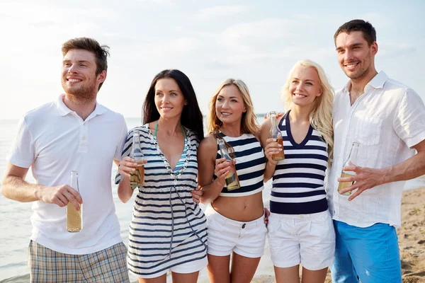 Içki şişeleri plajda arkadaşlarıyla gülümseyen — Stok fotoğraf
