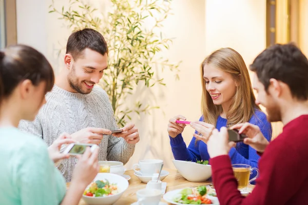 Vänner med smartphones tar bild av mat — Stockfoto